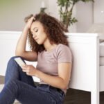 Worried teenage girl using mobile phone in her room
