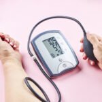 measuring blood pressure with electronic medical device over pink background