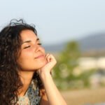 Woman relaxing and enjoying the sun in a warmth park at sunset